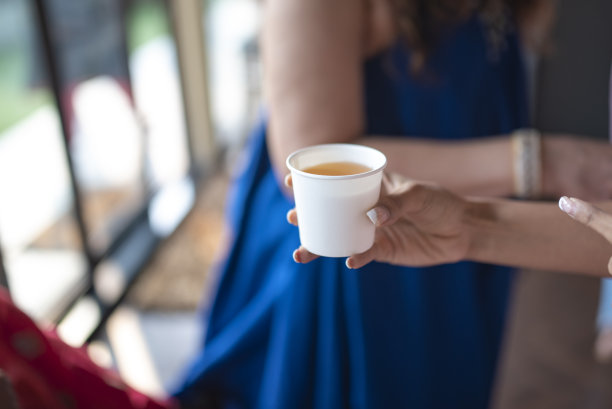 在一张咖啡馆照片中，女人拿着一杯一次性柠檬茶图片下载
