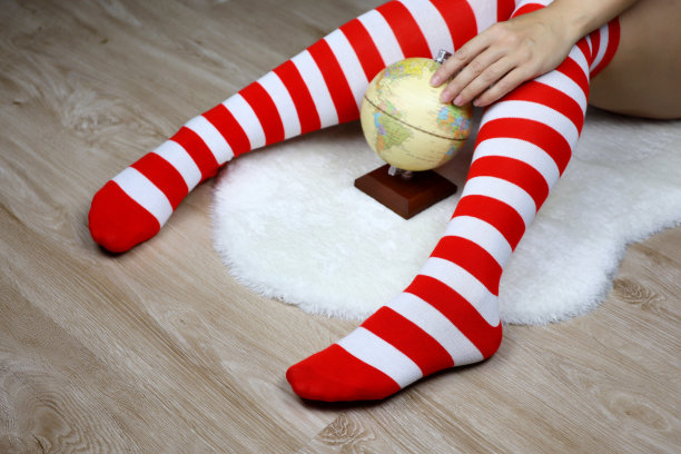 女腿在圣诞膝袜，散焦点的看法，妇女坐与地球仪上的白色毛皮地毯图片下载