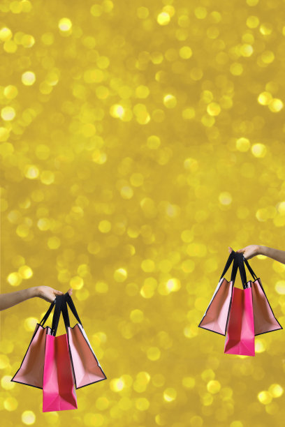 购物袋在女性手中以金色的柏格背景，柏格背景与复制空间垂直格式图片下载