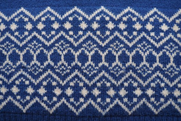 提花针织图案。用白色丝线织成，以蓝色为底色，呈菱形和之字形。圣诞节或新年的几何装饰。冬季时尚现代传统民间服饰点缀图片下载