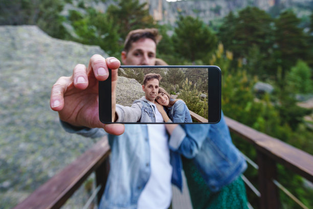 正面的快乐的夫妇照片模型在屏幕智能手机户外。图片下载