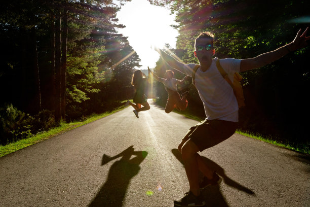 前视图的朋友跳跃在道路的中间。图片下载