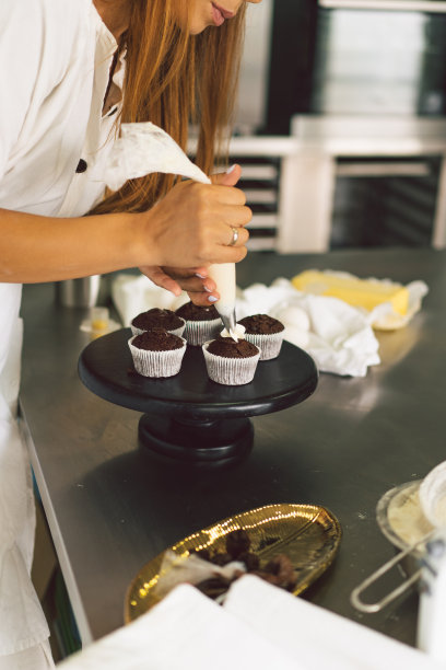 糖果商女孩正在准备纸杯蛋糕。面粉制品或甜点的概念配料。图片下载
