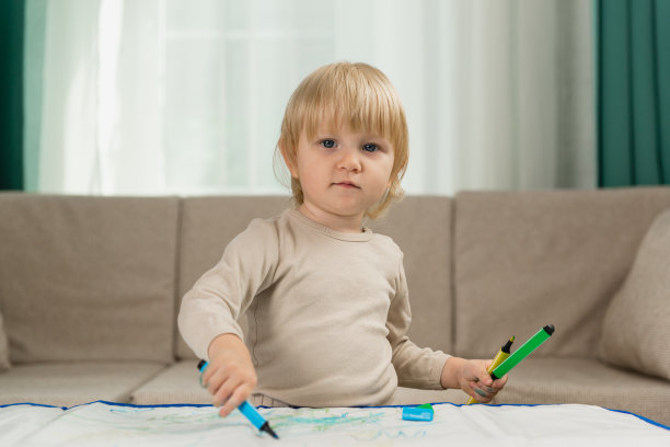 一个穿着睡衣的快乐小女孩在家里的桌子上用儿童水笔画画图片下载