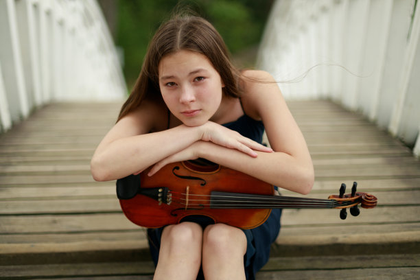 美丽的棕色头发的亚洲女孩的外表，在自然小提琴。音乐家在自然界中。古典音乐图片下载