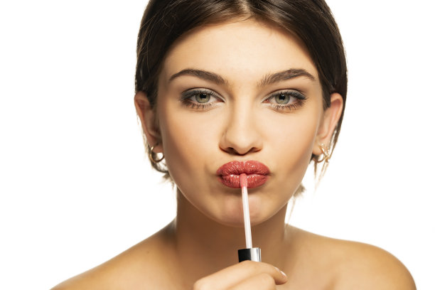 一个年轻漂亮的女人在涂唇彩图片下载