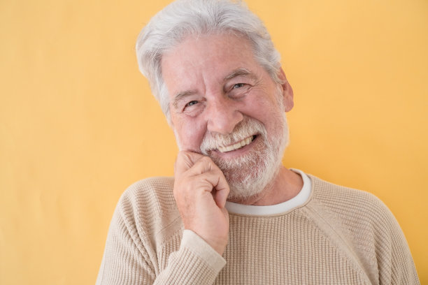 照片上美丽的老人与白胡子和头发看着相机微笑在黄色的背景图片下载
