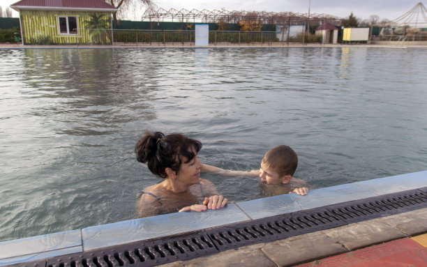 高兴的孙子和奶奶在温泉池游泳。图片下载