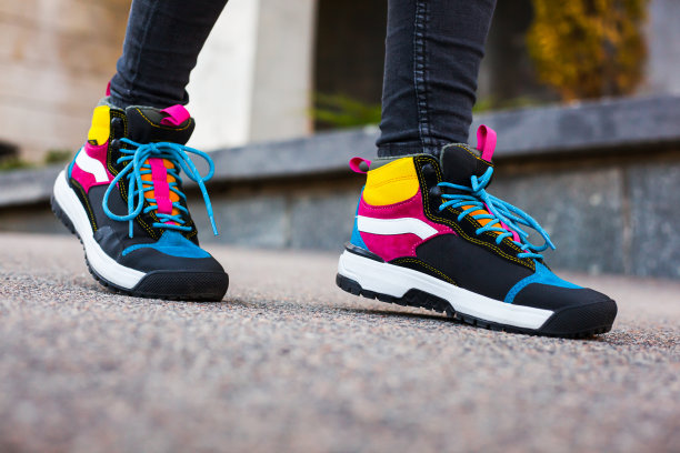 运动多色高靴在女性腿上的黑色牛仔裤的背景上的城市图片下载