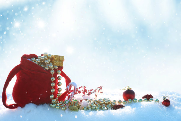 寒假背景与红色圣诞老人袋。圣诞球和礼物盒在雪地上。以冷杉树枝做新年贺卡。图片下载