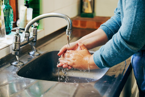 一个女人在厨房水槽里洗手图片下载