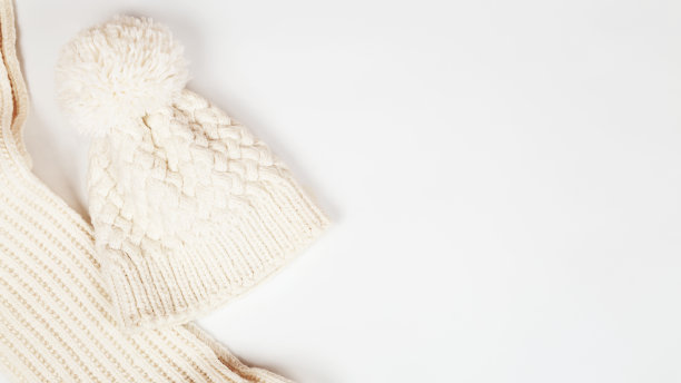 用温暖的线编织的围巾、管子或衣领和带圆球的白色帽子。秋冬配件。复制空间，顶视图，平铺图片下载