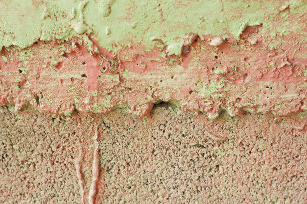 纹理照片，一个不均匀的涂抹混凝土砌块墙与肮脏的绿色和红色的油漆，它与空白的复制空间的文字或背景使用。图片下载