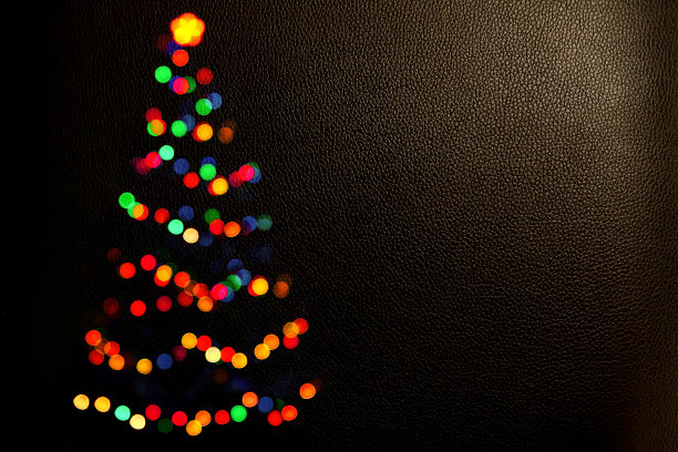 圣诞背景彩灯彩灯。圣诞树的散景剪影。模糊的光。祝新年贺卡快乐。副本的空间。黑暗空间里的圣诞树图片下载