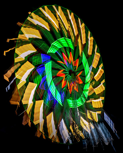 巨大的彩色摩天轮在夜晚旋转。慢快门缩放平移图像一个旋转的巨大的车轮在夜间。图片下载