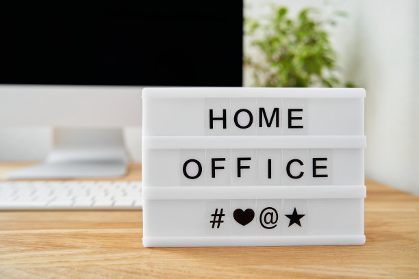 灯箱上写着“家庭办公室”。灯箱放在一张木制的桌子上，背景中有一个模糊的屏幕。图片下载