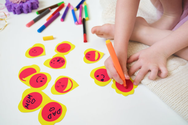 孩子坐在地板上做有趣的情人节卡片，有趣的工艺品图片下载