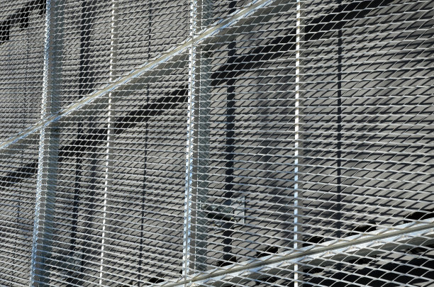 建筑的钢覆层，带有扩展的金属网格结构。镀锌灰色网保护工业建筑。蓝色的天空与银色的背景形成对比图片下载