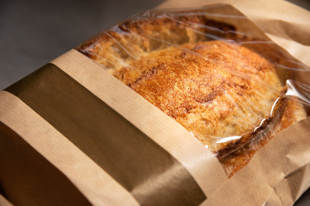 白面包:装在纸袋里的一条白色手工制作的热面包，白色背景上有透明的衬垫。健康食品。自制的天然产品图片下载