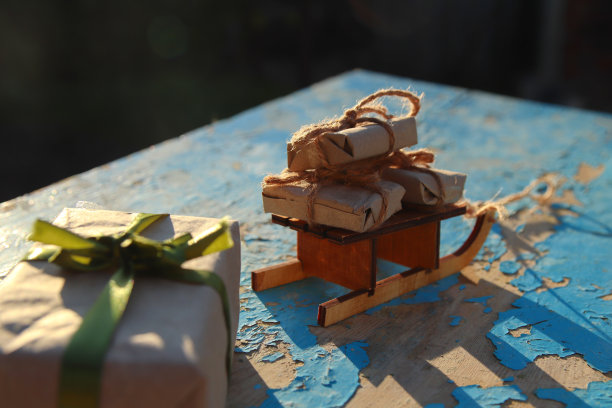 圣诞礼物。包装工艺古董礼品盒躺在木制玩具雪橇上蓝色的旧木制背景。礼品盒在牛皮纸。节日的概念。圣诞节,圣诞节的背景。许多生态呈现图片下载