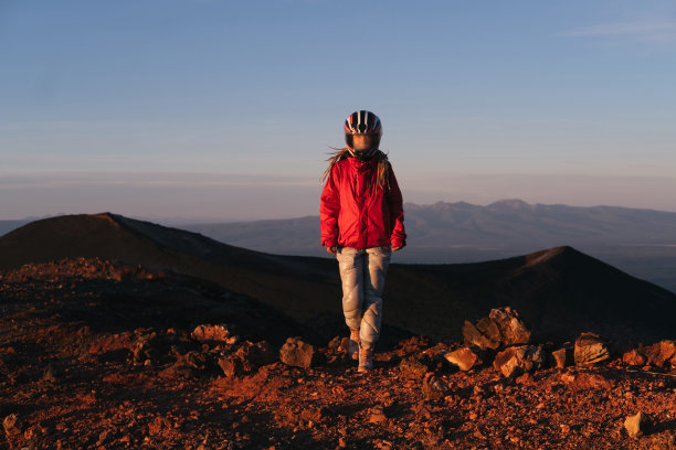 在火山谷戴着摩托车头盔的妇女。雾蒙蒙的玻璃，红色的山丘，就像另一个星球上的火星景观图片下载