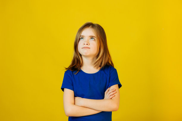 沮丧的孩子双手交叉在黄色的背景在工作室图片下载