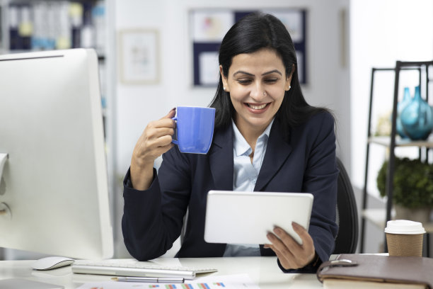 迷人的女商人坐在室内办公室的桌子上，工作。库存图片图片下载