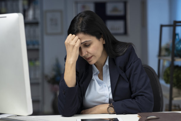 迷人的女商人坐在室内办公室的桌子上，工作。库存图片图片下载