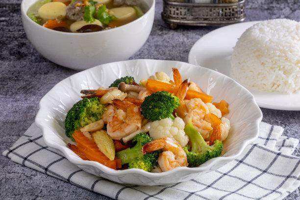 将炒好的蔬菜和虾仁放入一个白色的盘子中图片下载