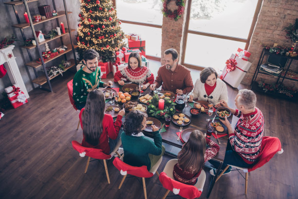 照片肖像老年人庆祝圣诞节与孙子坐在节日餐桌吃菜在室内公寓图片下载