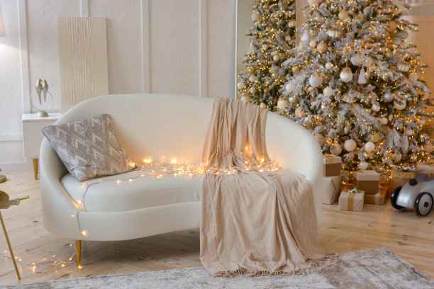 圣诞节的房间。白色的沙发，枕头，格子图案和花环，背景是装饰精美的圣诞树。新年快乐，圣诞快乐!图片下载