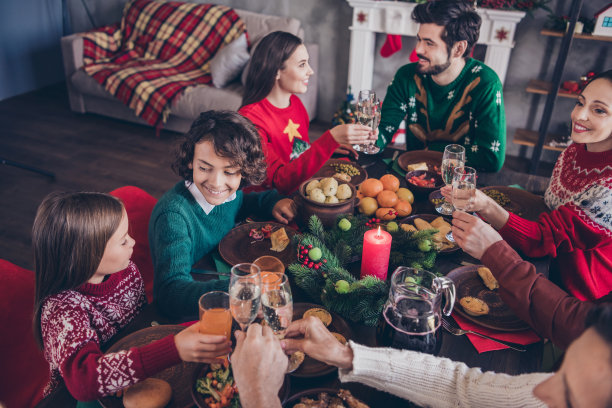照片肖像大家庭告诉吐司坐在节日的桌子上，在冬季假期圣诞节与孩子们喝果汁图片下载