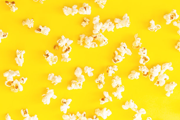 在头顶的黄色背景上散落着电影爆米花图片下载