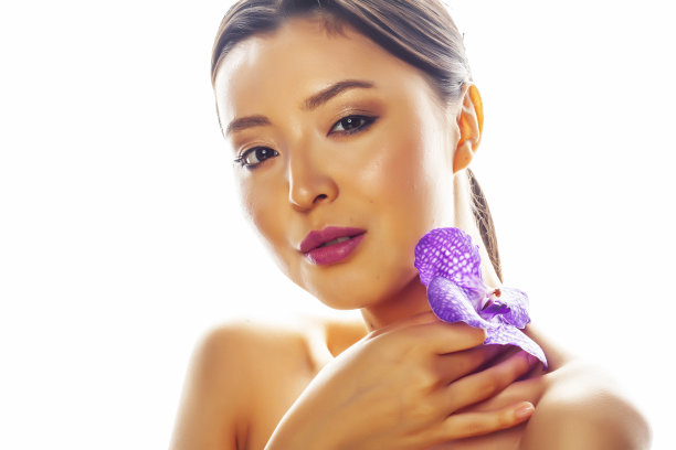 年轻漂亮的亚洲女人与花紫色兰花孤立在白色的背景，温泉人的概念图片下载