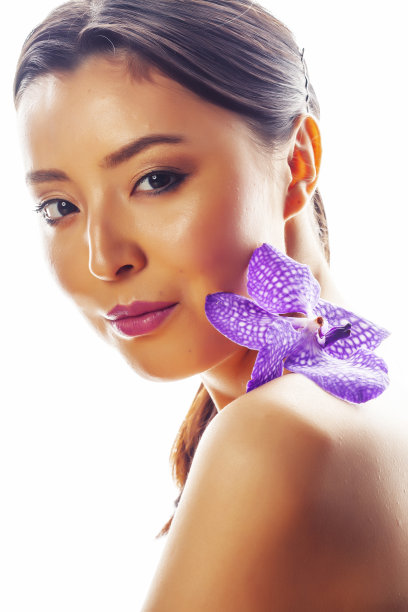 年轻漂亮的亚洲女人与花紫色兰花孤立在白色的背景，温泉人的概念图片下载