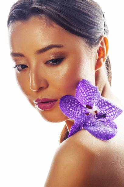 年轻漂亮的亚洲女人与花紫色兰花孤立在白色的背景，温泉人的概念图片下载