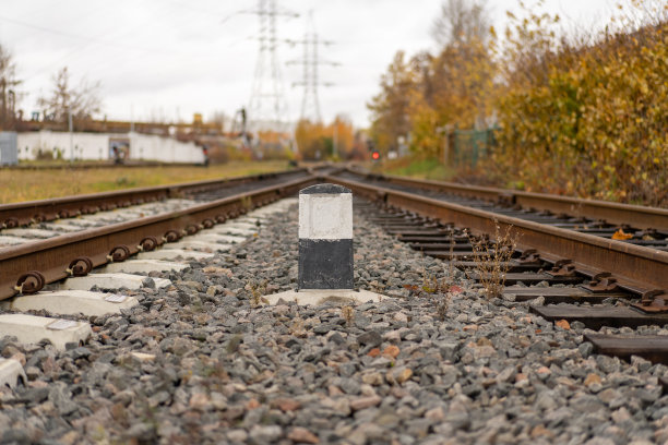 一张老铁路的照片和灰色的石头旁边的黑白圆柱。火车概念，绿树图片下载
