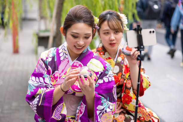 穿着和服的年轻女性在观光地点拍摄视频-美食报道图片下载