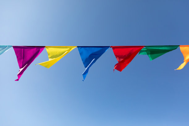 以蓝天为背景，用五彩三角制作的节日彩带。庆祝晚会。图片下载