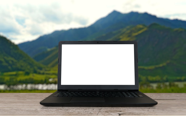 空白屏幕笔记本电脑在老化的灰色桌子上，模糊的山脉背景图片下载