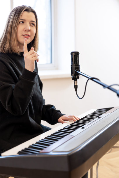 坐在麦克风前弹奏钢琴的年轻女子。图片下载
