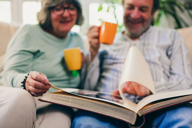 老夫妇看着年轻时的纪念相册，与现代相比，使用纸质照片的概念，集中在相册上图片下载