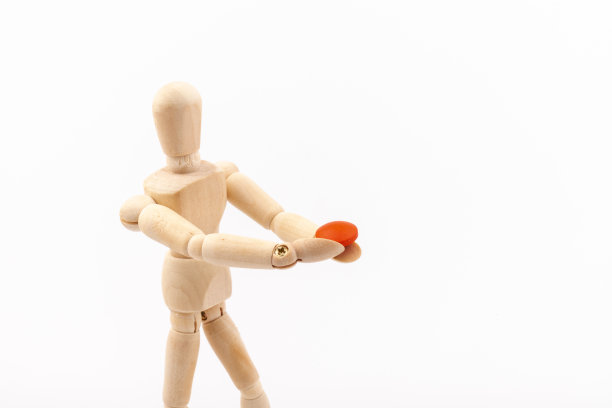 白色背景上有药丸的木制人体模型。药品和补充剂的概念。图片下载