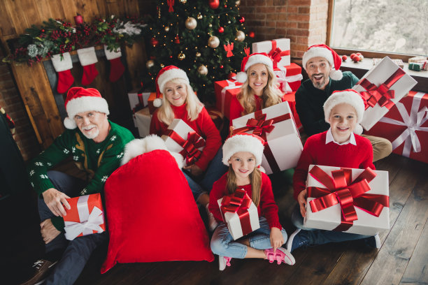 家庭朋友的照片小的童年孙子退休的人退休的人祖父母坐在圣诞老人帽子礼物圣诞节在室内的房子里图片下载