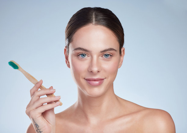一个迷人的年轻女子的工作室肖像与她的牙刷在一个灰色的背景摆姿势图片下载