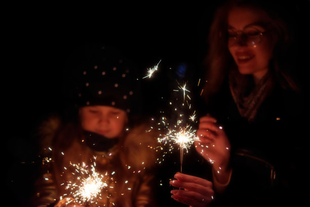 母亲和女儿拿着燃烧的烟火在外面图片下载