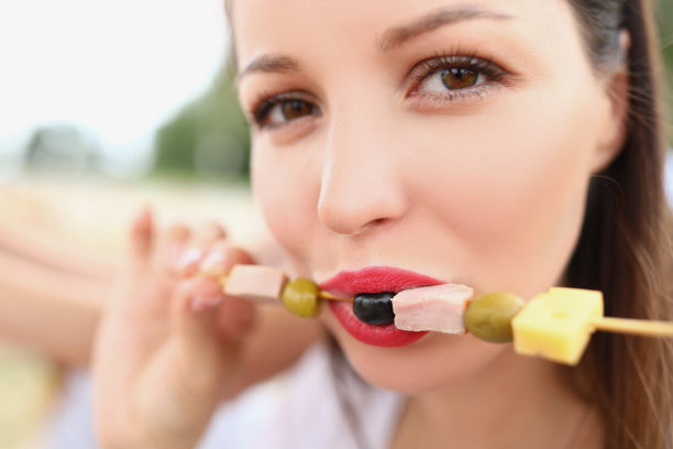 一个女人吃着橄榄和火腿串图片下载