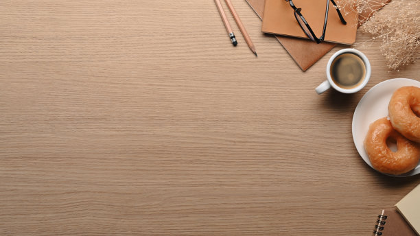 上图是美味的甜甜圈、咖啡和木桌上的笔记本。图片下载