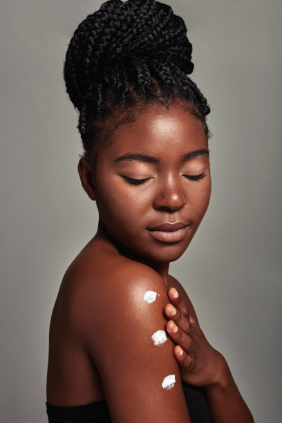 一个迷人的年轻女子在灰色背景上涂抹润肤霜的工作室镜头图片下载