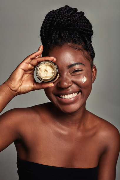 一个迷人的年轻女子在灰色背景上涂抹润肤霜的工作室镜头图片下载